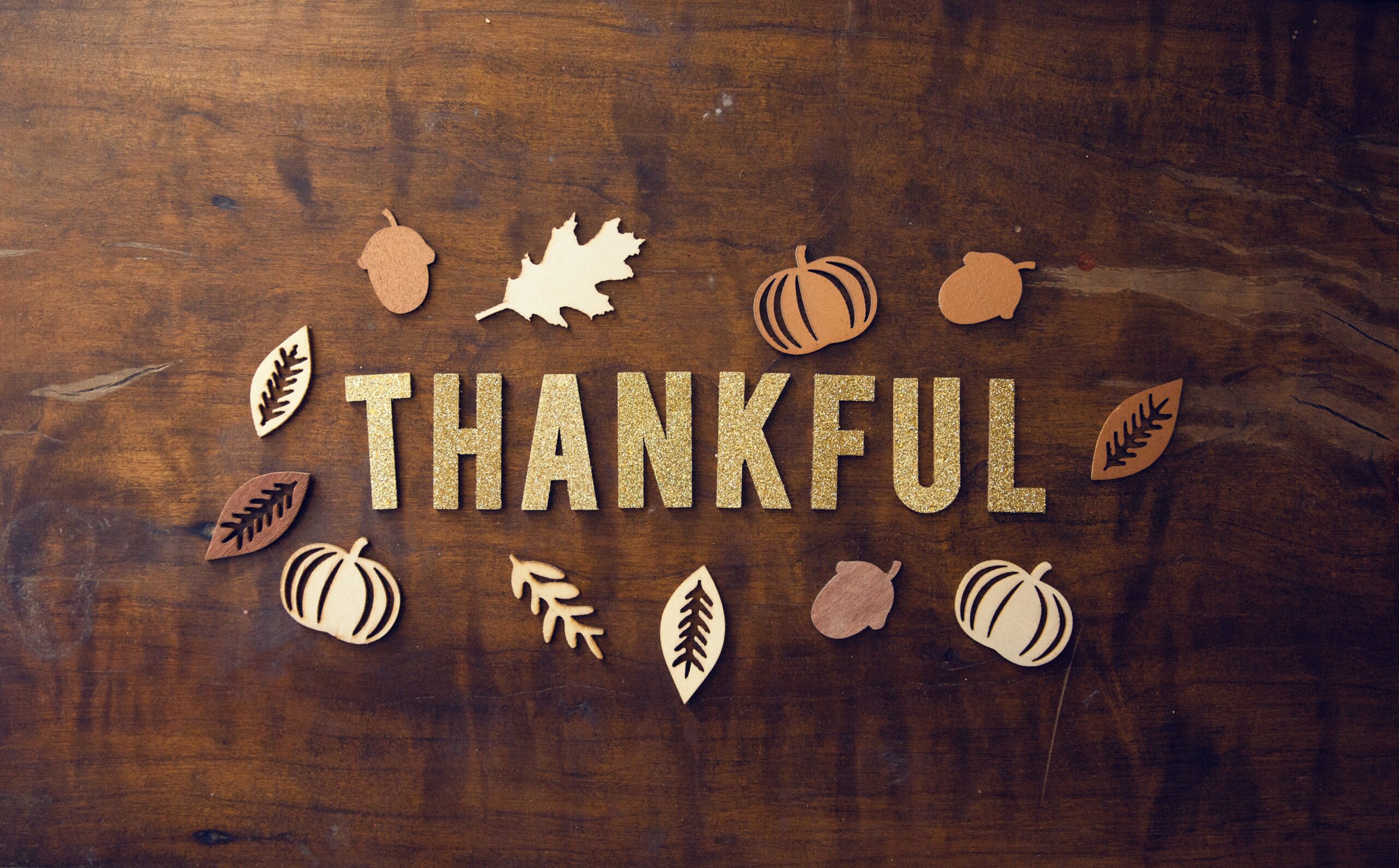 The word "thankful" spelled out artistically with Thanksgiving and fall icons surrounding it.