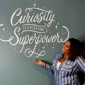 Shonnah Hughes with sign stating "Curiosity is everyones superpower"
