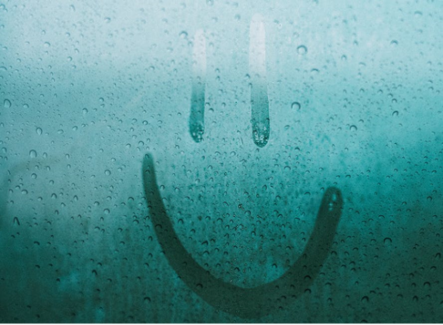 A smiley face drawn by a finger on a foggy mirror.