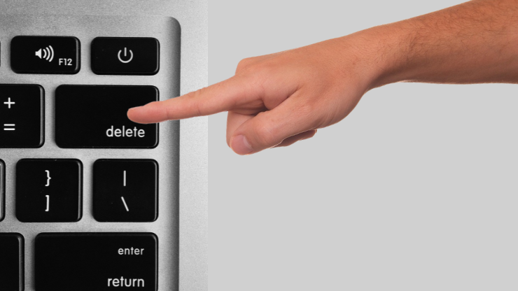 A finger pressing the "Delete" button on a keyboard.