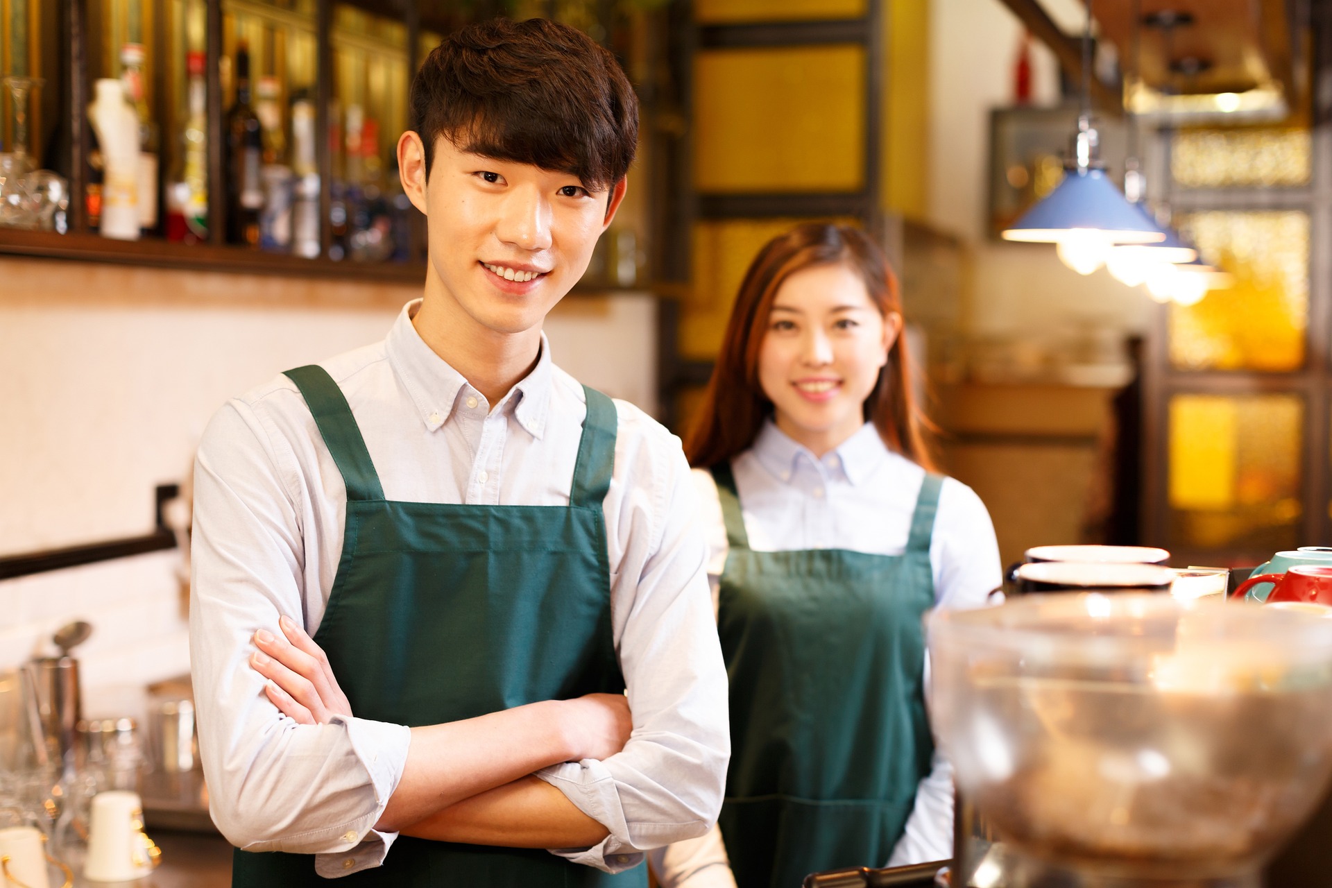 Two restaurant employees wearing green aprons