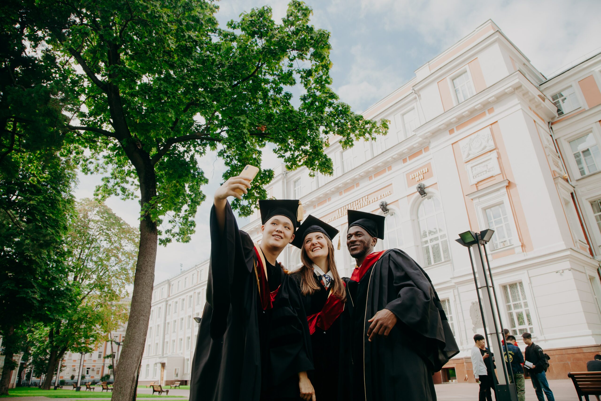 3 students take a selfie at their college graduation