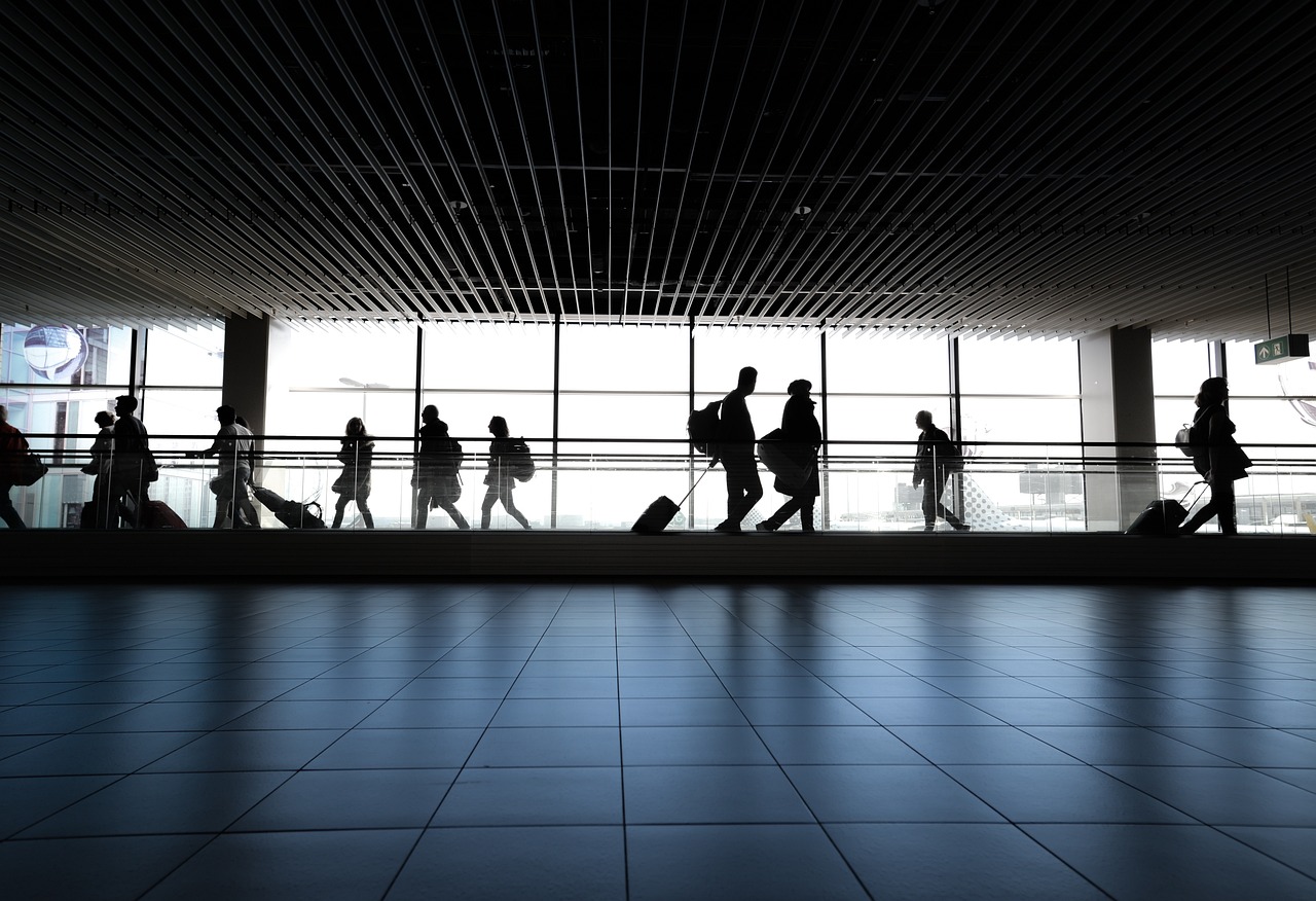People walking along a pathway through a busy airport.