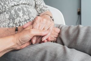 A senior citizen holds hands with a caregiver. Resident experience in assisted living facilities has become a competitive requirement.